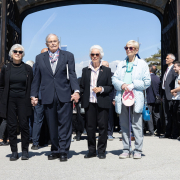 Hana Berger Moran, Mark Olsky, Eva Clarke sowie Katja Sturm-Schnabl gehen Hand in Hand durch das Tor des ehemaligen Konzentrationslagers Mauthausen.
