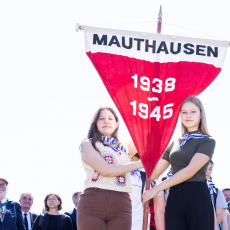 Jugendliche halten den Wimpel mit der Aufschrift "Mauthausen 1938 - 1945" bei der Internationalen Gedenk- und Befreiungsfeier in Mauthausen 2022 © MKÖ/Sebastian Philipp